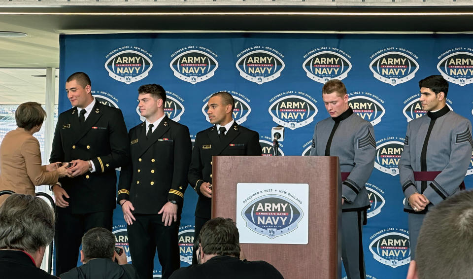 Massachusetts Gov. Maura Healey presents players with replicas of Paul Revere bowls to welcome them to the state for the Army-Navy game during a news conference at Gillette Stadium in Foxborough, Mass., Wednesday, Nov. 29, 2023. From left are players: Navy defensive end Jacob Busic, linebacker Will Harbour, quarterback Xavier Arline, Army linebacker Leo Lowin, and defensive back Jimmy Ciarlo. (AP Photo/Jimmy Golen)