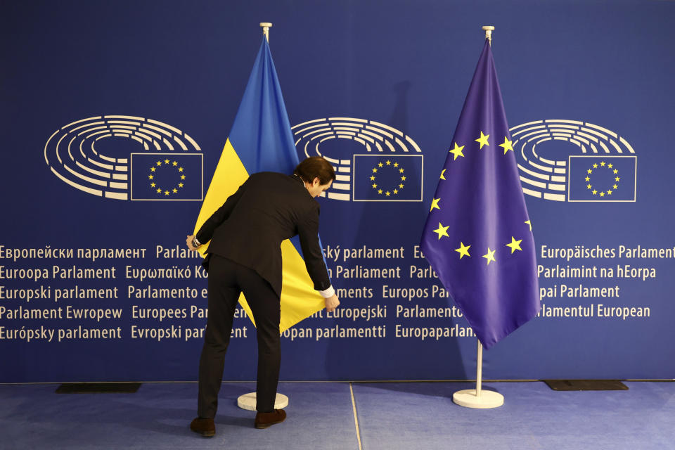 A worker stretches the Ukrainian flag before Ukraine's President Volodymyr Zelenskyy arrival at the European Parliament in Brussels, Belgium, Thursday, Feb. 9, 2023. (AP Photo/Olivier Matthys)