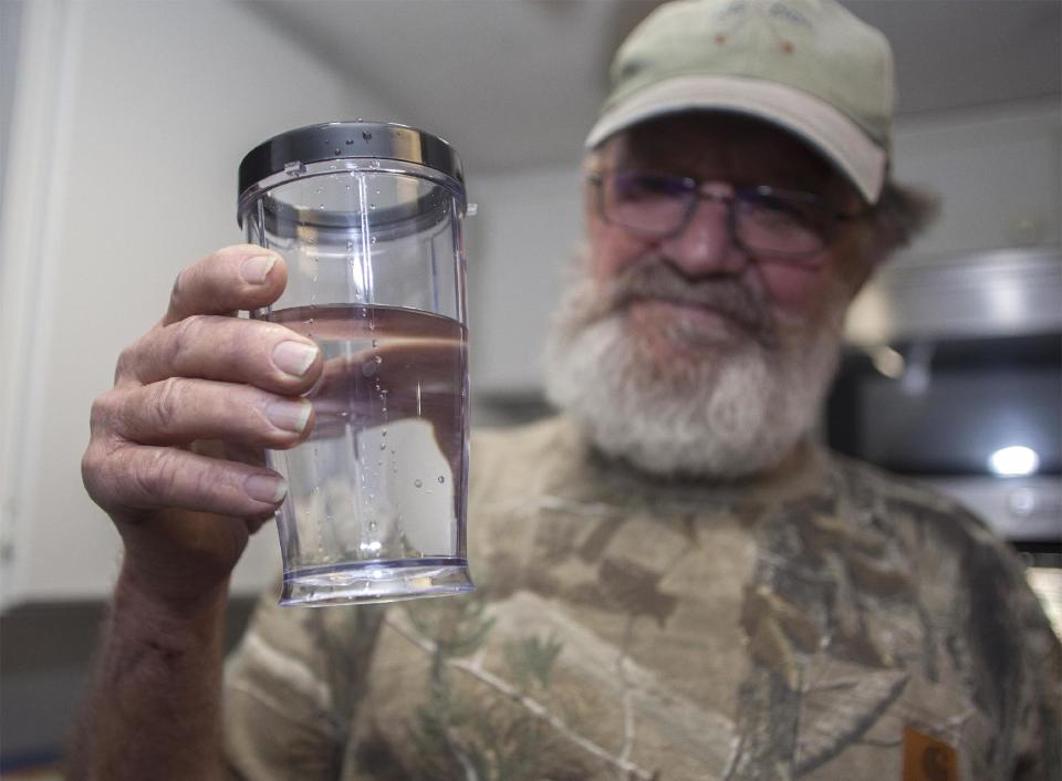 Flemington Road community member Sam Malpass of Wilmington, N.C. holds a glass of water from his home on Wednesday, Feb. 19, 2014. Malpass and his wife Pat are part of a small community near L.V. Sutton Complex operated by Duke Energy they feel could be polluting well water with spill off and seepage from large coal ash ponds. “If you want to know what it’s like living near a coal ash pond, this is it,” said Malpass, 67, a retired carpenter and Vietnam veteran. “We’re afraid to drink the water because we don’t know what’s in it. We can’t eat the fish because we don’t know if it’s safe anymore. It’s changed our lives out here.” (AP Photo/Randall Hill)