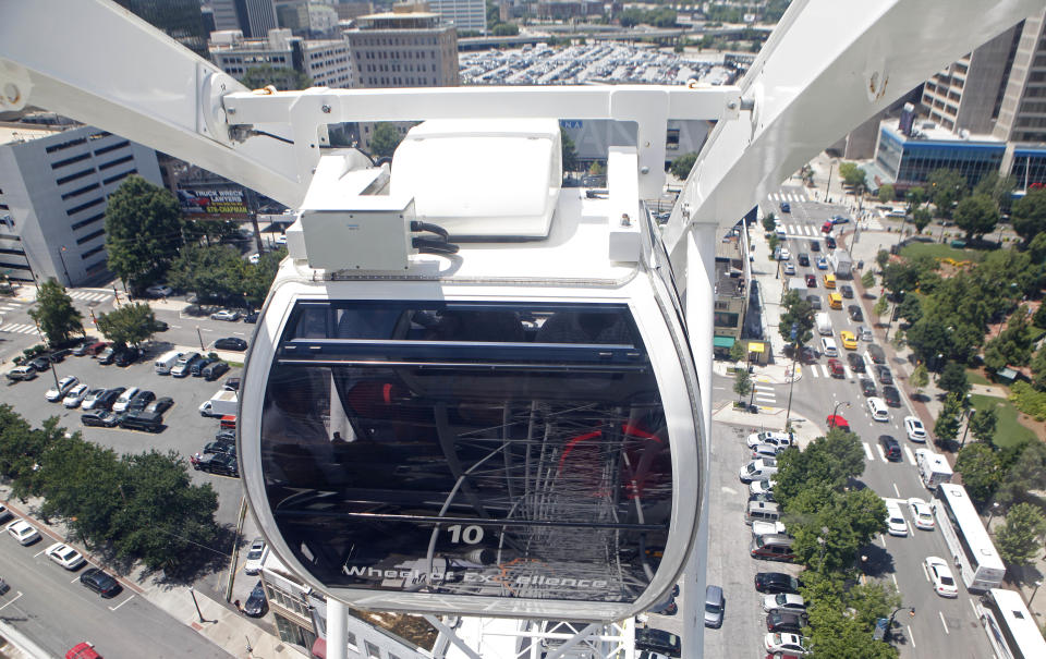 A climate-controlled gondola of the SkyView, a 200-foot tall Ferris wheel, rises over Atlanta, Tuesday, July 16, 2013, in Atlanta. The giant ferris wheel opened to the public Tuesday. (AP Photo/Jaime Henry-White)