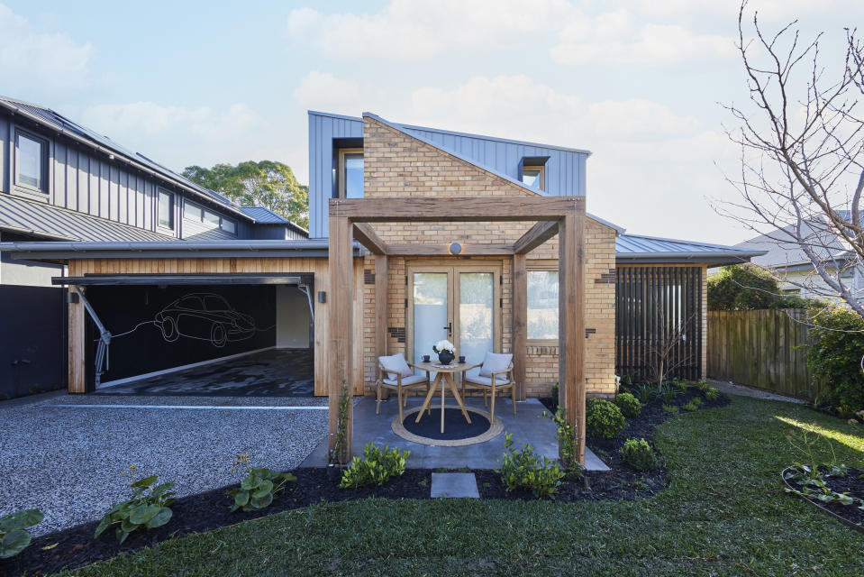 A shot of the arbor at the front of the house and the garage on the left and grass on the right. 