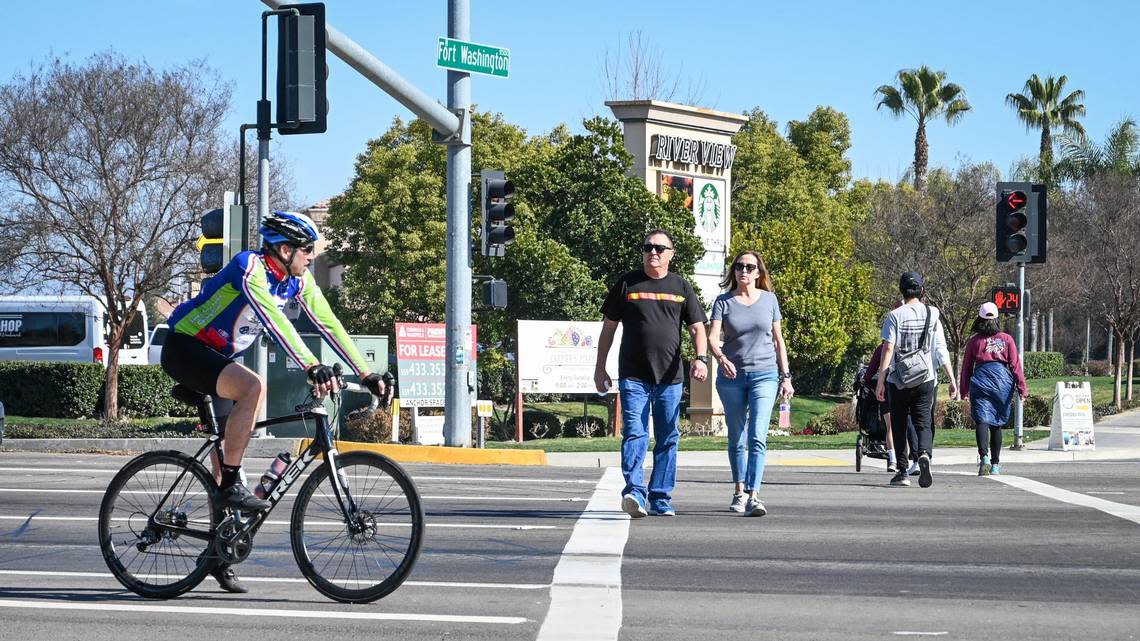 Pedestrians cross Friant Road at Fort Washington near Woodward Park in Fresno on Thursday, Feb. 10, 2022. The intersection has become an area of concern for safety after recent deaths from passing vehicle traffic.