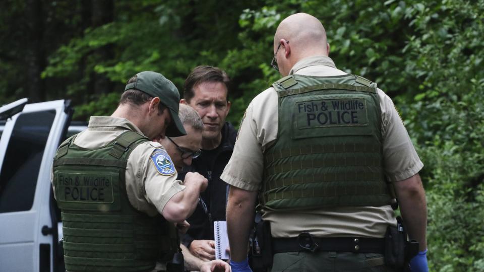 Pilizisten sprechen mit einem Hilfssheriff und einem Gerichtsmediziner, nachdem ein Berglöwe einen Radfahrer getötet hat. Foto: Alan Berner/The Seattle Times/AP