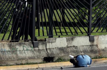 A member of the riot security forces fires a gun through the fence of an air force base at David Jose Vallenilla, who was fatally injured during clashes at a rally against Venezuelan President Nicolas Maduro’s government, in Caracas, Venezuela June 22, 2017. REUTERS/Carlos Garcia Rawlins