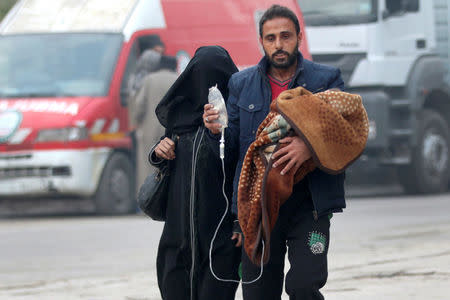 A man carries a child with an IV drip as he flees deeper into the remaining rebel-held areas of Aleppo, Syria. REUTERS/Abdalrhman Ismail
