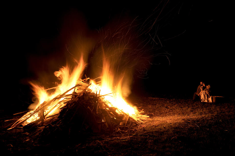 A couple sits by a campfire, during the Romula Fest historic reenactment festival in the village of Resca, Romania, Saturday, Sept. 3, 2022. (AP Photo/Vadim Ghirda)