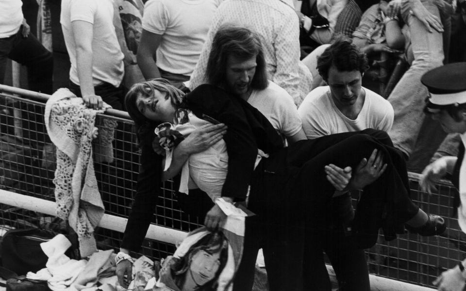 An unconscious teenage girl is carried away following an incident at a David Cassidy concert, London 1974 - Getty