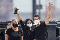 Michael Kovrig, center right, waves to media as his wife Vina Nadjibulla, centre left, and sister Ariana Botha, left, after his arrival at Pearson International Airport in Toronto, Saturday, Sept. 25, 2021. China, the U.S. and Canada completed a high-stakes prisoner swap Saturday with joyous homecomings for Kovrig and Michael Spavor, two Canadians held by China and for an executive of Chinese global communications giant Huawei Technologies charged with fraud. (Frank Gunn /The Canadian Press via AP)