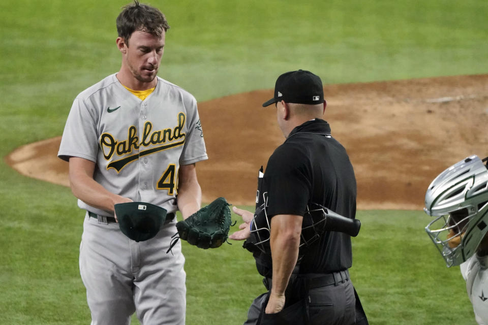 Umpire Scott Barry checks Oakland Athletics starting pitcher Chris Bassitt for illegal substances in the second inning of a baseball game Thursday, June 24, 2021, in Arlington, Texas. (AP Photo/Louis DeLuca)