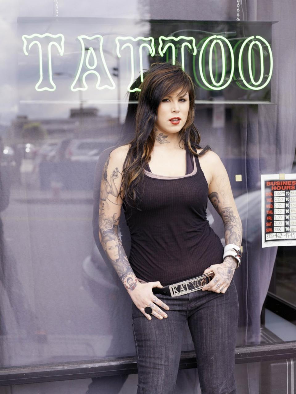 Kat Von D on "Miami Ink" in front of a storefront with a neon "TATTOO" sign.