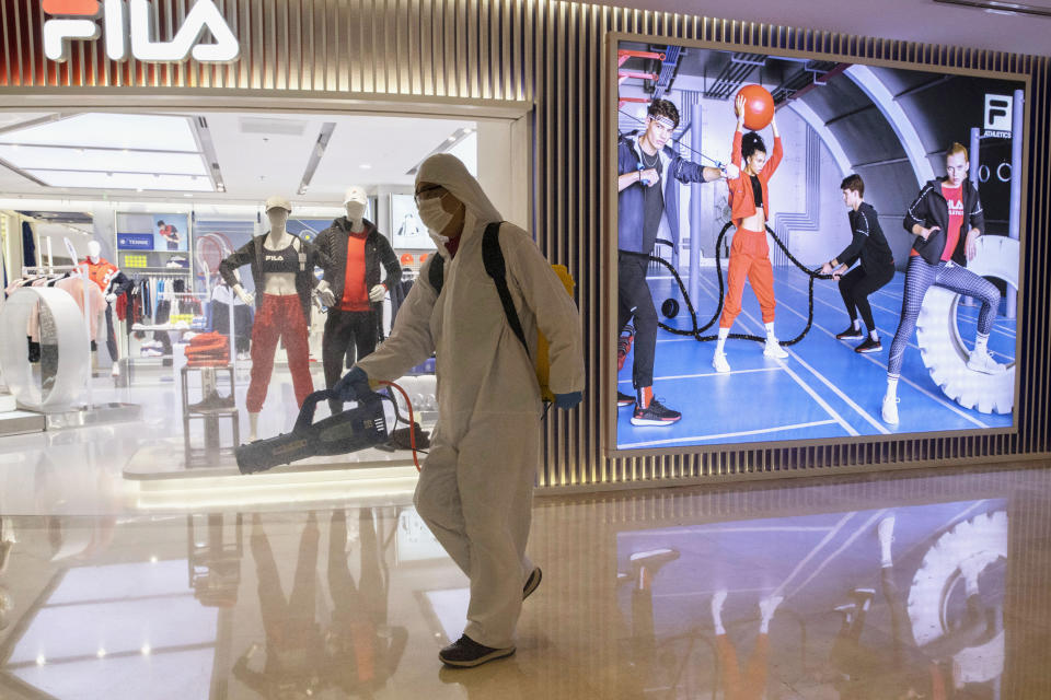 In this photo taken Wednesday, Feb. 12, 2020, a worker sprays disinfectant in a deserted mall in Beijing, China. Millions of Chinese workers and entrepreneurs are bearing the rising costs of an anti-virus campaign that has shut down large sections of the economy. The government has imposed restrictions nationwide that have stalled travel and sales of real estate and autos. (AP Photo/Ng Han Guan)