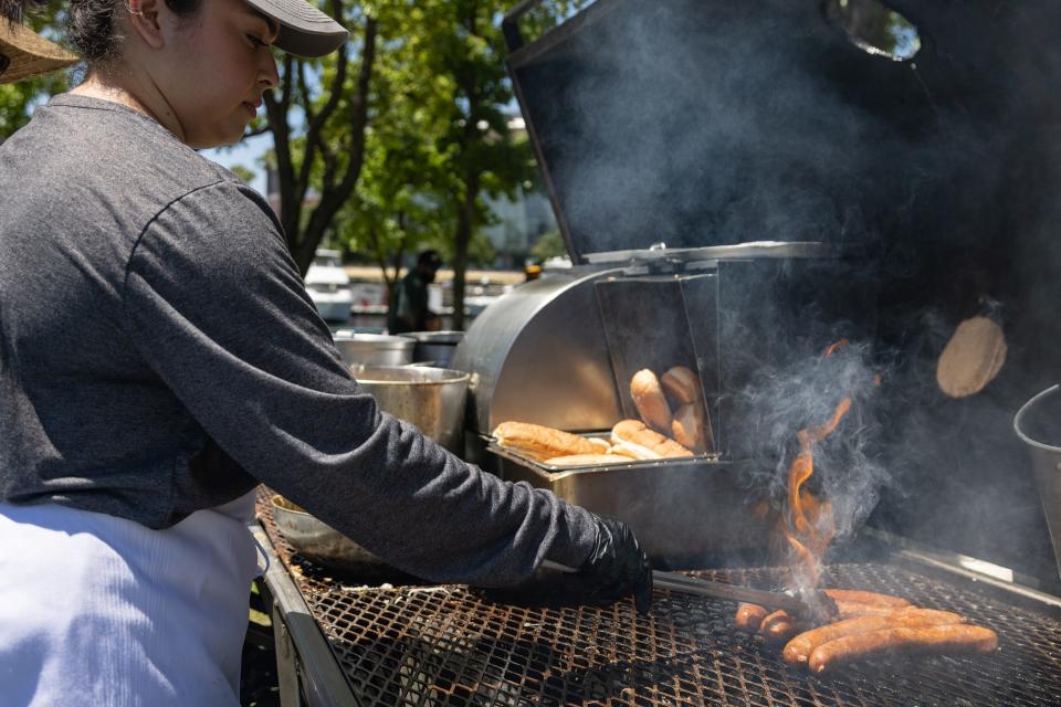 Jacqueline Aguilar grills the Lockeford Brats during Stockton Flavor Fest on Saturday, May 20, 2023, at Weber Point. The event had culinary vendors, food trucks, entertainment, performances, kids activities, craft beers and more.