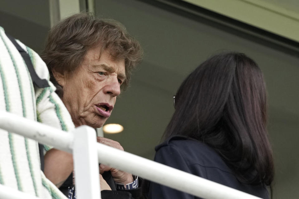 Mick Jagger of the Rolling Stones interacts with a woman in the gallery during the second day of the fifth Ashes Test match between England and Australia at The Oval cricket ground in London, Friday, July 28, 2023. (AP Photo/Kirsty Wigglesworth)