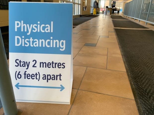 A sign encourages physical distancing at the Saskatoon COVID-19 vaccine clinic at Prairieland Park. (Guy Quenneville/CBC - image credit)