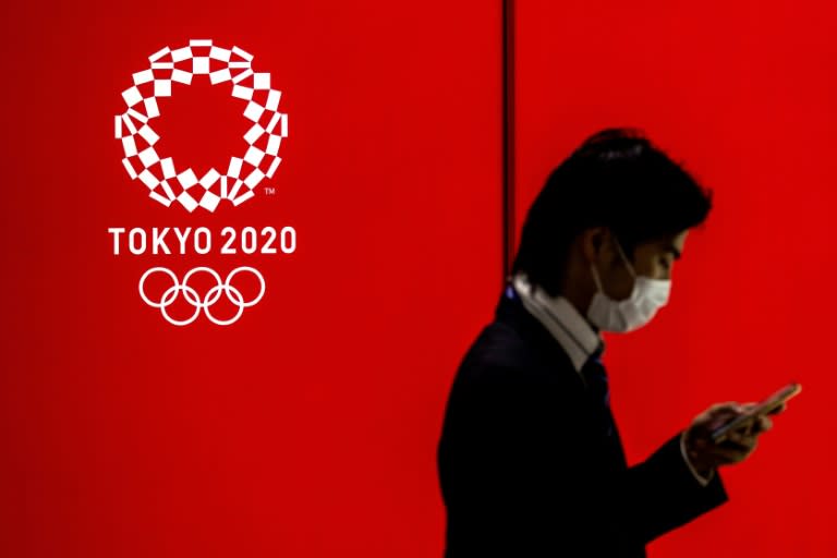 A masked man walks past a logo of the Tokyo 2020 Olympics (Behrouz MEHRI)