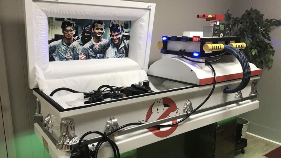 A white coffin outfitted in the decor and items of Ghostbusters