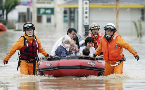 Local residents sit in a boat as they are rescued from a flooded area at a hospital in Kurashiki - Credit: Reuters
