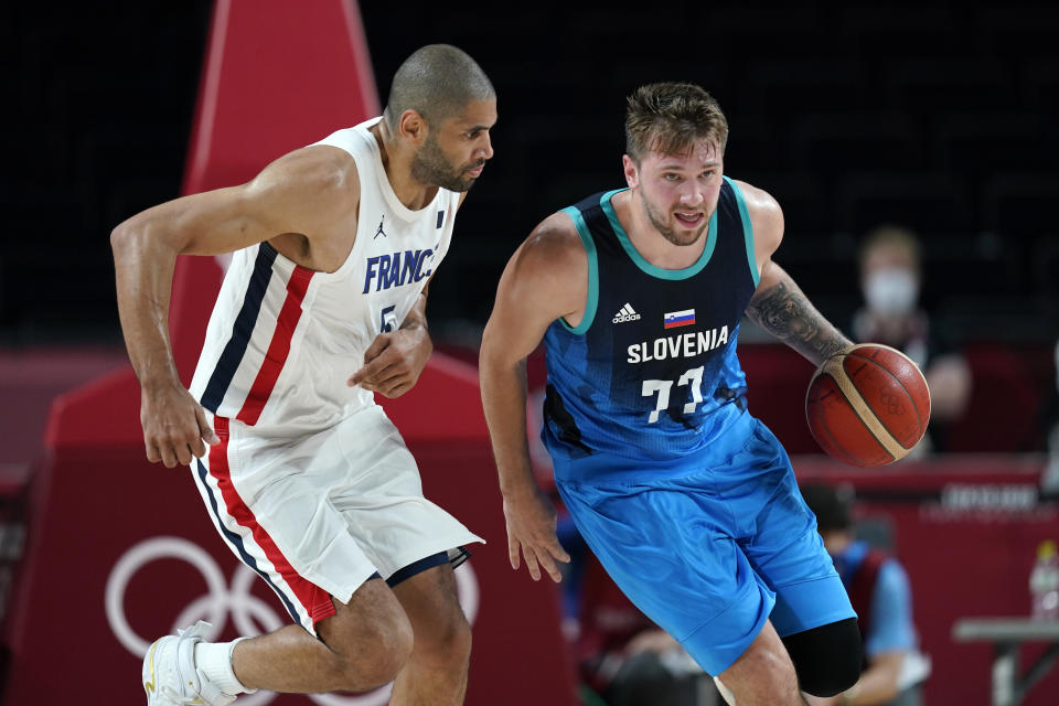 Slovenia's Luka Doncic (77) drives up court past France's Nicolas Batum (5) during a men's basketball semifinal round game at the 2020 Summer Olympics, Thursday, Aug. 5, 2021, in Saitama, Japan. (AP Photo/Charlie Neibergall)