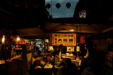 Tourist eat at the Raohe street Night Market in Taipei, Taiwan January 18, 2017. REUTERS/Tyrone Siu