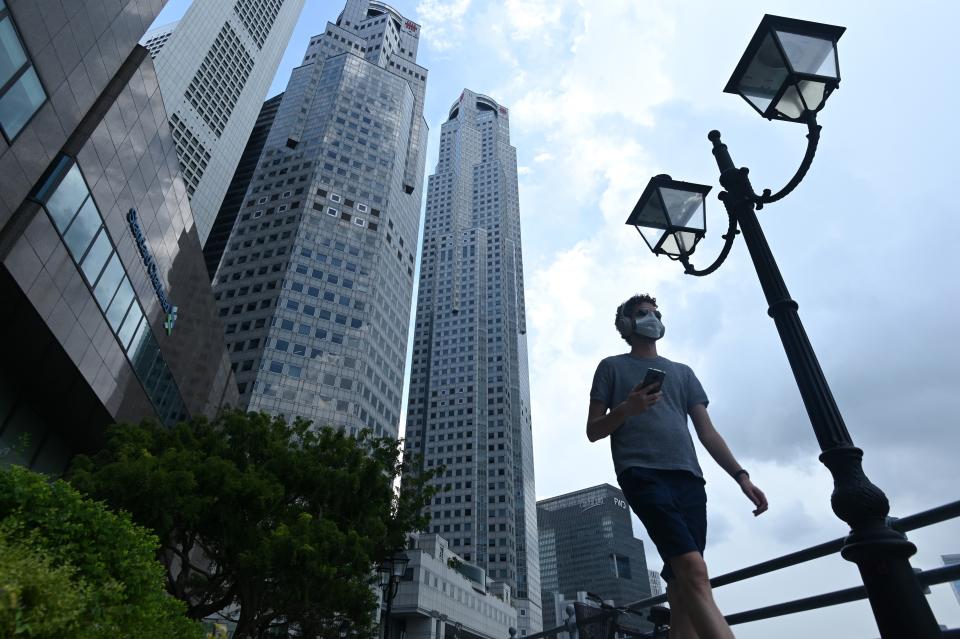 A man walks past commercial buildings in the financial business district in Singapore on June 11, 2020, as the city state eased its partial lockdown restrictions aimed at curbing the spread of the COVID-19 coronavirus. (Photo by ROSLAN RAHMAN / AFP) (Photo by ROSLAN RAHMAN/AFP via Getty Images)