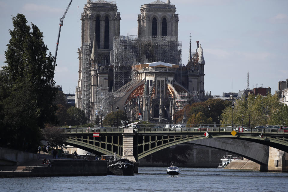 In this photo taken Tuesday Sept. 17, 2019 in Paris, a hydrofoil boat SeaBubble sails on the Seine river, in front of Notre Dame cathedral. Paris is testing out a new form of travel - an eco-friendly bubble-shaped taxi that zips along the water, capable of whisking passengers up and down the Seine River. Dubbed Seabubbles, the vehicle is still in early stages, but proponents see it as a new model for the fast-changing landscape of urban mobility. (AP Photo/Francois Mori)