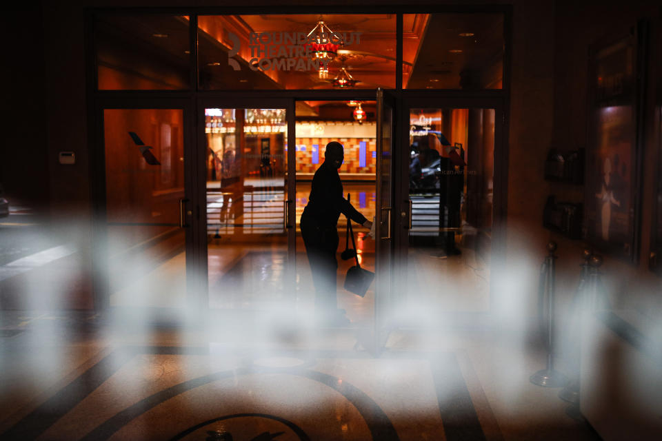 A custodian cleans the lobby of the Roundabout Theatre Company in Times Square, Thursday, March 12, 2020, in New York. New York City Mayor Bill de Blasio said Thursday he will announce new restrictions on gatherings to halt the spread of the new coronavirus in the coming days. For most people, the new coronavirus causes only mild or moderate symptoms. For some it can cause more severe illness. (AP Photo/John Minchillo)