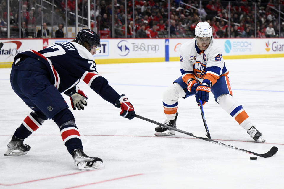 New York Islanders left wing Anders Lee, right, battles for the puck against Washington Capitals defenseman Alexander Alexeyev, left, during the first period of an NHL hockey game, Monday, April 10, 2023, in Washington. (AP Photo/Nick Wass)