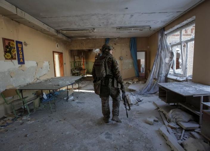 A Ukrainian serviceman is seen in a destroyed building of school at a frontline in Donetsk region