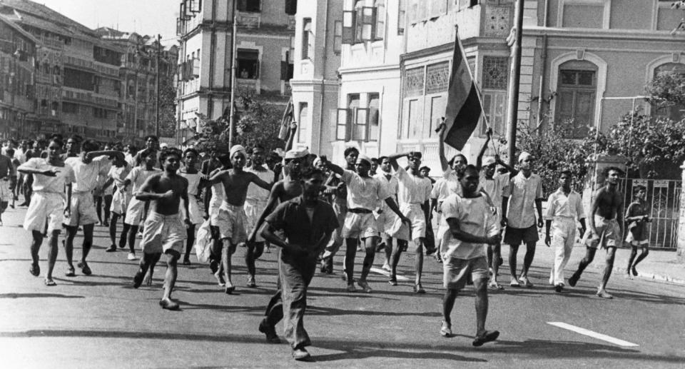 Men of the Royal Indian Navy stream through the streets in Bombay after burning a UK flag during anti-British demonstrations, on February 25, 1946. The flag carried in the foreground is that of the Congress party. The smaller flag near centre is the Muslim League flag. (AP Photo)