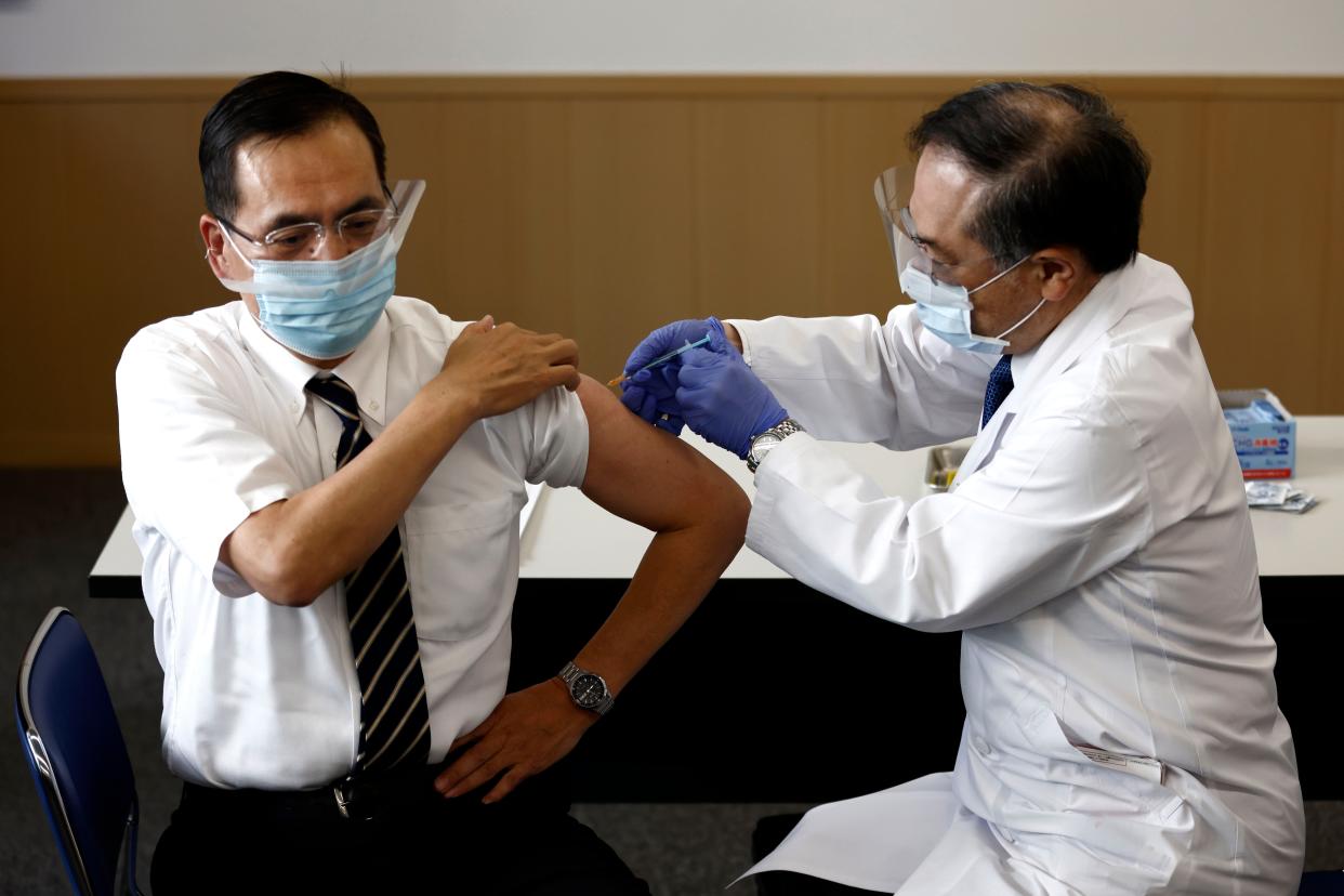 Tokyo Medical Center director Kazuhiro Araki, left, receives a dose of COVID-19 vaccine in Tokyo on Wednesday, Feb. 17, 2021.