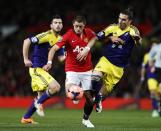 Manchester United's Javier Hernandez (C) is tackled by Swansea City's Chico Flores (R) during their English FA Cup third round soccer match at Old Trafford in Manchester, northern England January 5, 2014. REUTERS/Russell Cheyne (BRITAIN - Tags: SPORT SOCCER)