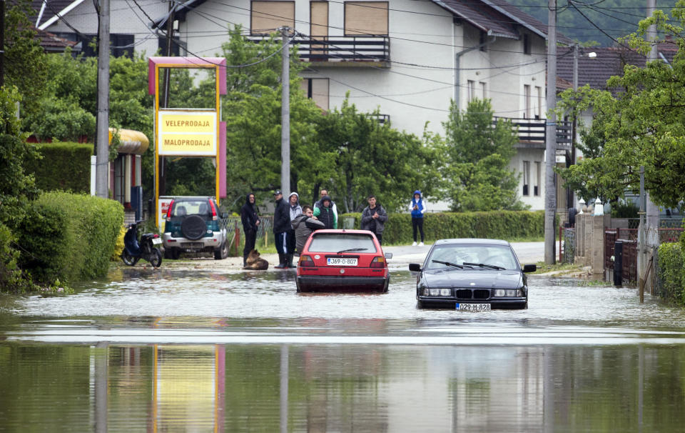 Residents attempt to drive through a flooded street in Sanski Most, Bosnia-Herzegovina, Tuesday, May 14, 2019. Homes and roads have been flooded in parts of Bosnia after rivers broke their banks following heavy rains, triggering concerns Tuesday of a repeat of floods five years ago when dozens died. (AP Photo/Darko Bandic)