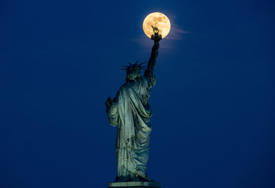 The Full Moon rises behind the Statue of Liberty in New York City, United States of America on May 22, 2024.