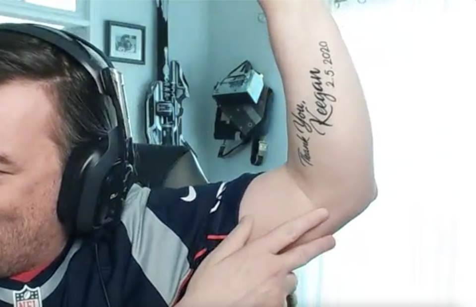 Wilson, wearing headphones, lifts up his arm to show the tattoo, which says: Thank You, Keegan, 2.5.2020.