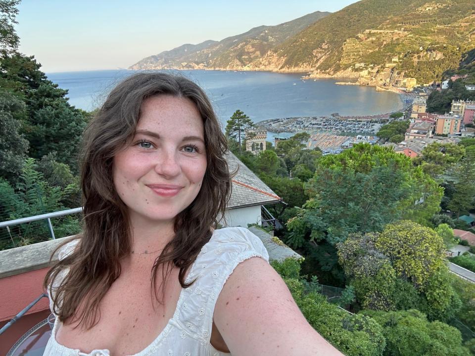 A woman stands in front a view of the ocean.