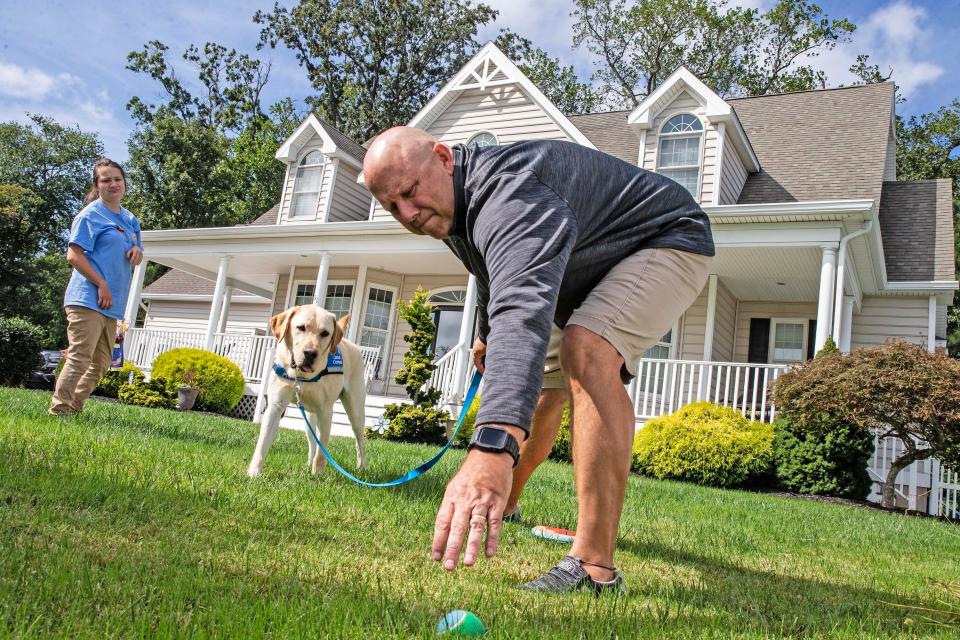 Kevin Tinsley reaches for a ball to play fetch with his daughter JazminÕs, at left, new service dog Bonus on the front lawn of the Tinsley family home in Rehoboth Beach, Wednesday, Sept. 27, 2023. Jazmin dreams of being a teacher and living independently one day.
