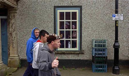 Youths walk past an empty building which has been covered with artwork to make it look more appealing, in the village of Bushmills on the Causeway Coast August 20, 2013. REUTERS/Cathal McNaughton