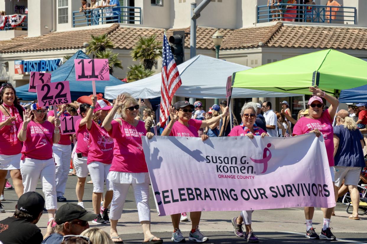 Women in pink shirts walking for Susan G Komen Breast cancer organization on Main Street during the 4th of July parade in Huntington Beach, Orange County, California