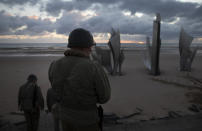 Two men in vintage US WWII uniforms walk toward the Les Braves monument at sunrise prior to a D-Day 76th anniversary ceremony in Saint Laurent sur Mer, Normandy, France, Saturday, June 6, 2020. Due to coronavirus measures many ceremonies and memorials have been cancelled in the region with the exception of very small gatherings. (AP Photo/Virginia Mayo)