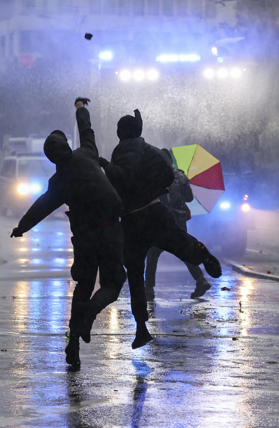 Left-wing demonstrators throw stones at a water cannon during riots in Leipzig, Germany, Saturday, Sept. 18, 2021. The campaign alliance "We are all Linx" had mobilized nationwide for the demonstration. (Jan Woitas/dpa via AP)