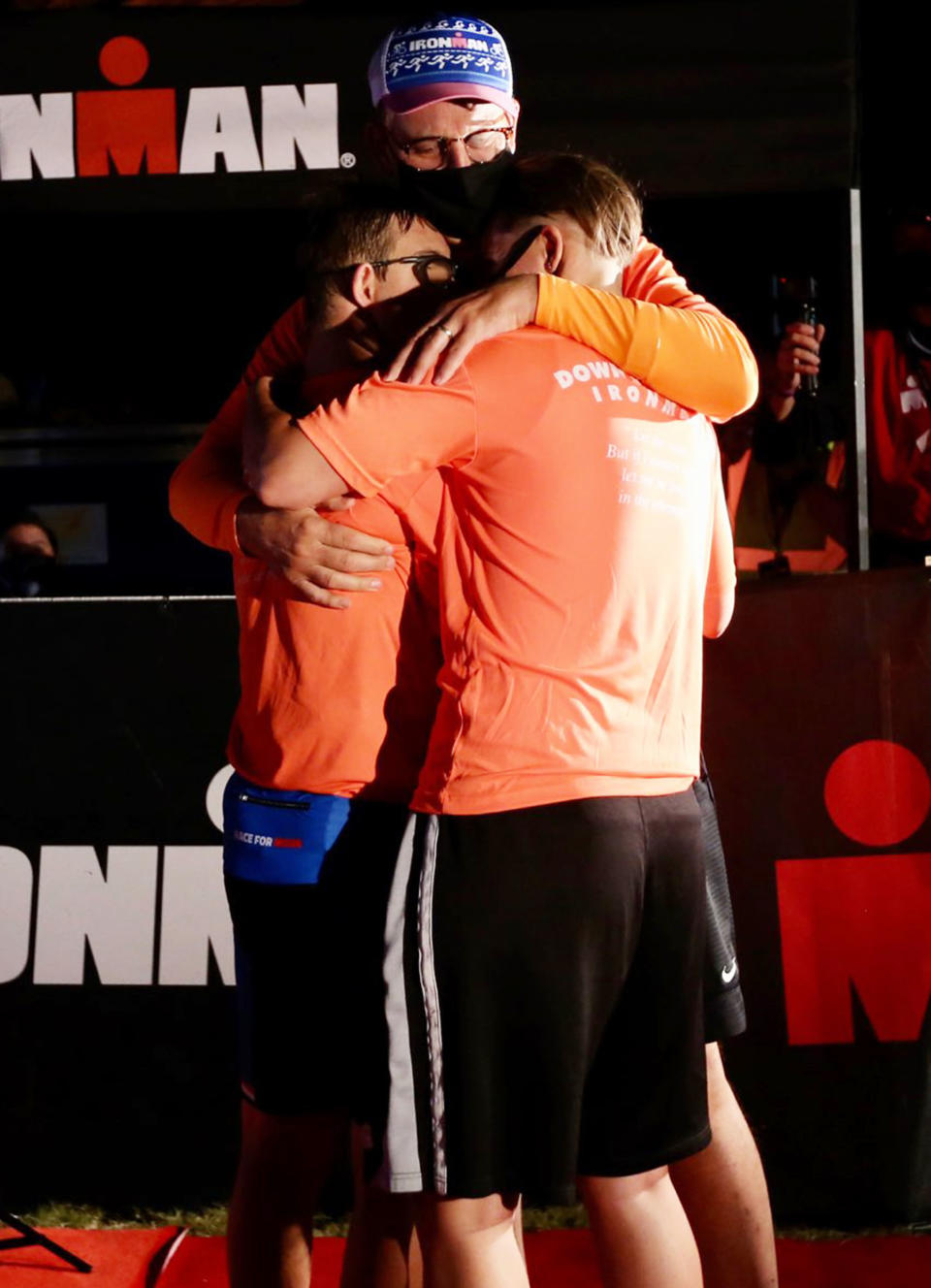 After becoming the first person with Down syndrome to both compete in and finish an Ironman, Chris Nikic celebrates with his dad, Nik, and training partner Dan Grieb.  (Courtesy Jonathan Bachman /  Getty Images)