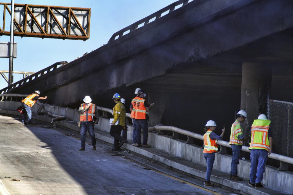 California Department of Transportation personnel inspect the structural integrity of a section of Interstate 10 that was severely damaged by a large fire near downtown Los Angeles on Saturday, Nov. 11, 2023. Authorities say firefighters have mostly extinguished the large blaze that burned trailers, cars and other things in storage lots beneath a major highway near downtown Los Angeles, forcing the temporary closure of the roadway. (AP Photo/Richard Vogel)