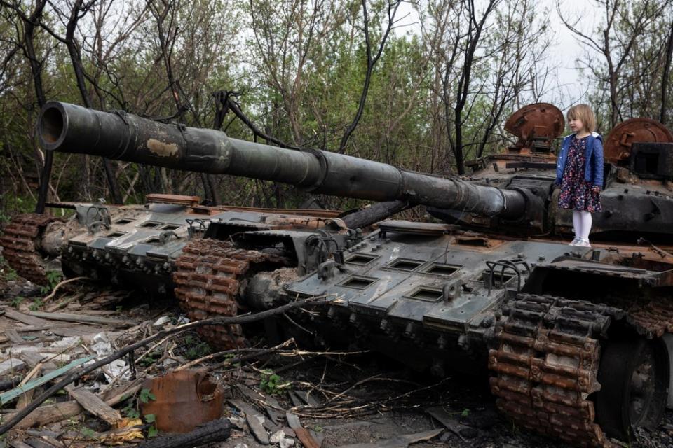 A child stands on a destroyed Russian tank near Makariv, Kyiv (Reuters)