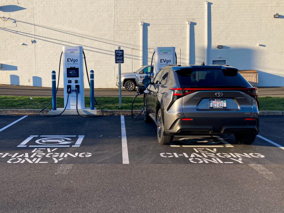 The 2023 Toyota bZ4X AWD Limited electric SUV parked in a parking lot, with a white building and blue skies in the background.