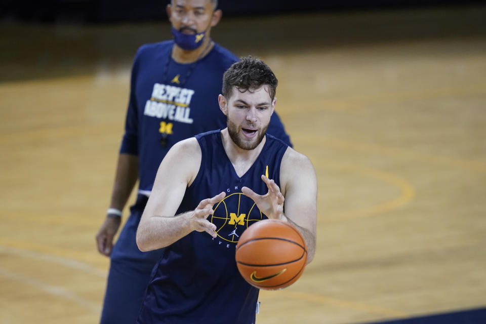 Michigan head basketball coach Juwan Howard, top, looks on as center Hunter Dickinson takes an inbound pass during an NCAA college basketball practice during media day, Friday, Oct. 15, 2021, in Ann Arbor, Mich. (AP Photo/Carlos Osorio)