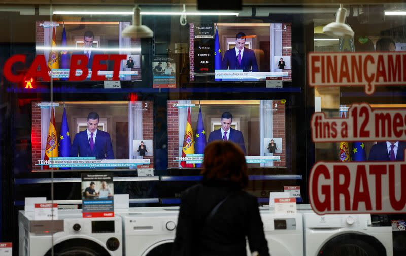 A person watches a TV broadcasting the statement by Spain's Prime Minister Sanchez, in El Masnou, north of Barcelona