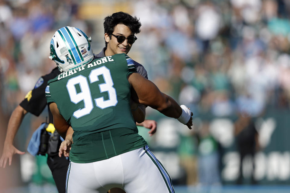 An unidentified spectator running on the field is restrained by Tulane defensive lineman Elijah Champaigne (93) during the first half of an NCAA college football game against Memphis in New Orleans, Saturday, Oct. 22, 2022. (AP Photo/Tyler Kaufman)