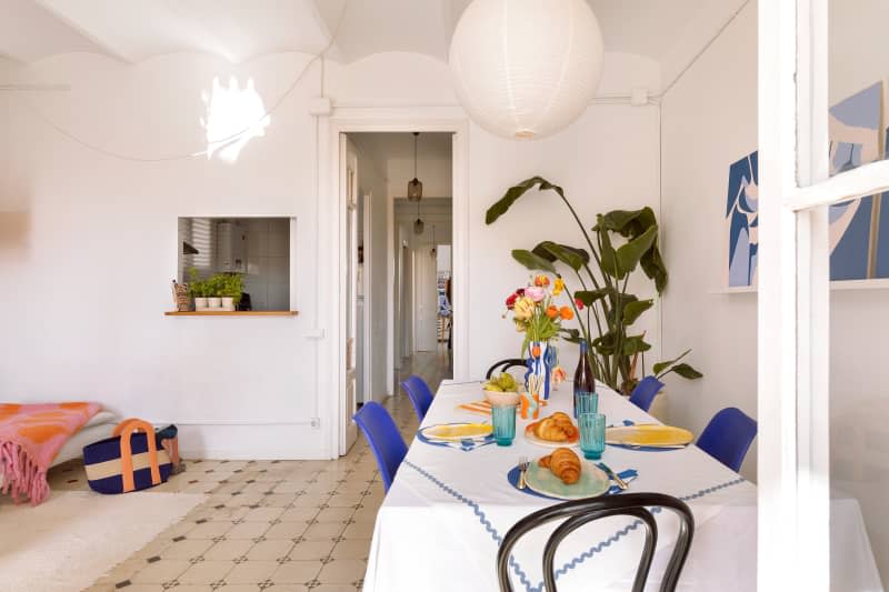 Dining room table with croissants and colorful glassware.