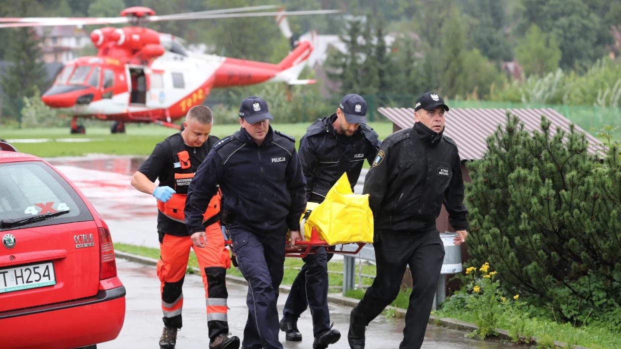 Polizisten tragen in Zakopane einen verletzten Touristen zu einem Krankenwagen. Foto: Grzegorz Momot/PAP