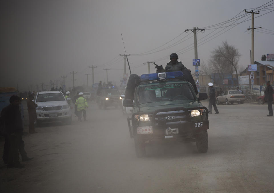 Afghan police men ride on top of their armored vehicle as they rush to the scene as Taliban militants attacked the main Afghan election commission's headquarters in the outskirts of Kabul, Afghanistan, firing on the compound with rocket-propelled grenades and heavy machine guns from a house outside its perimeter wall, Saturday, March 29, 2014. Dozens of employees and other people who had been inside the Independent Election Commission compound took cover in the basement, and no casualties were reported. But two warehouses were hit and set on fire, witnesses said. (AP Photo/Anja Niedringhaus)